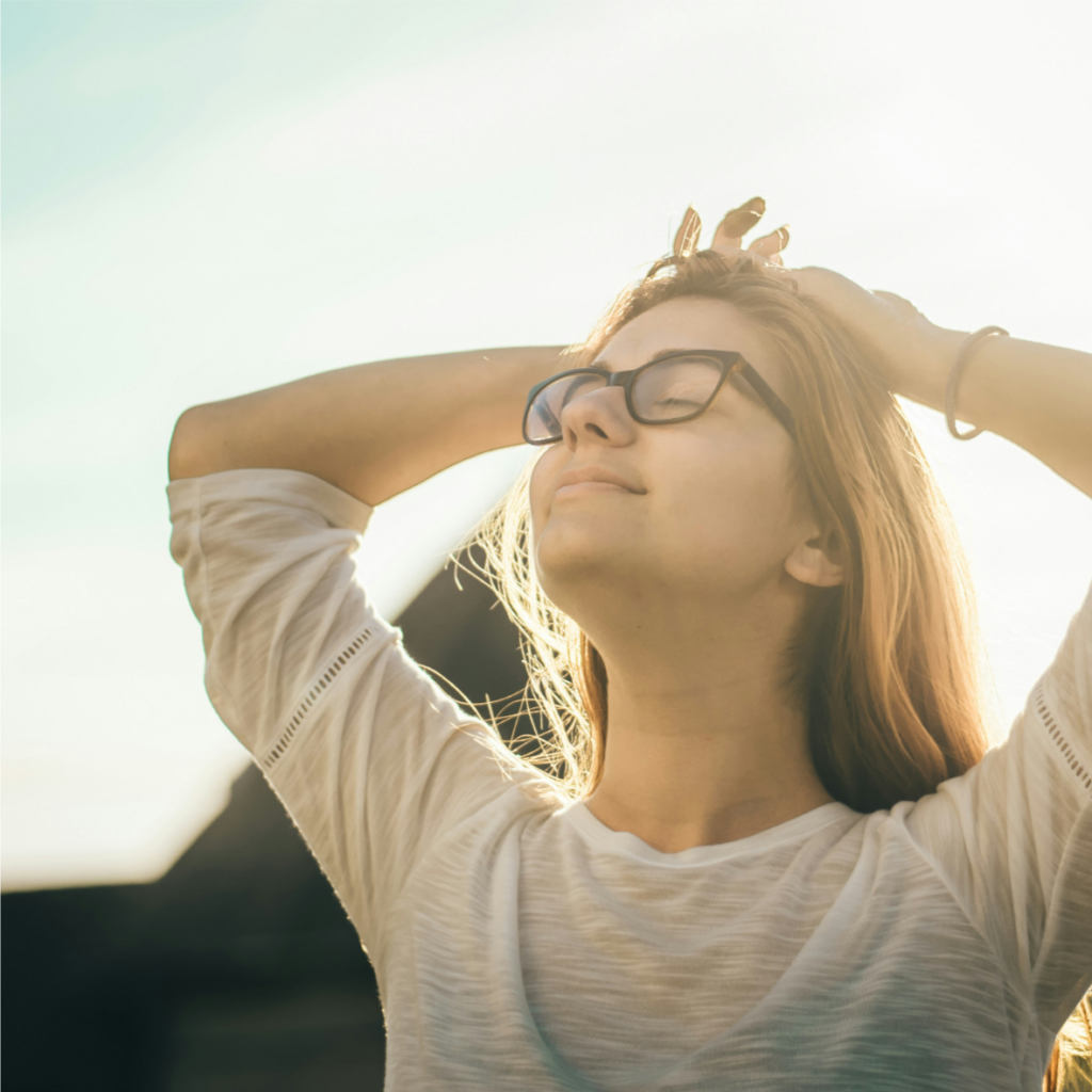 Une jeune femme à lunettes regarde le soleil.