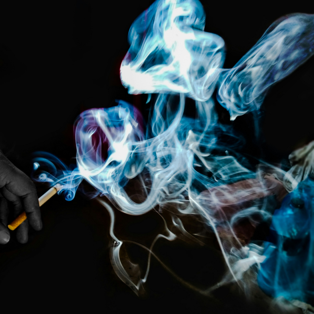 Une cigarette allumée avec de la fumée tourbillonnante sur un fond sombre, symbolisant le défi d'arrêter de fumer.