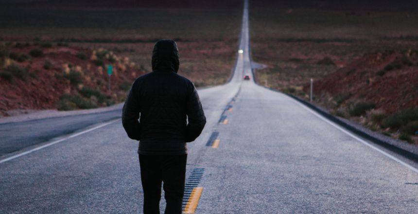 Un homme préparé mentalement avec l'hypnose marche sur une route déserte.